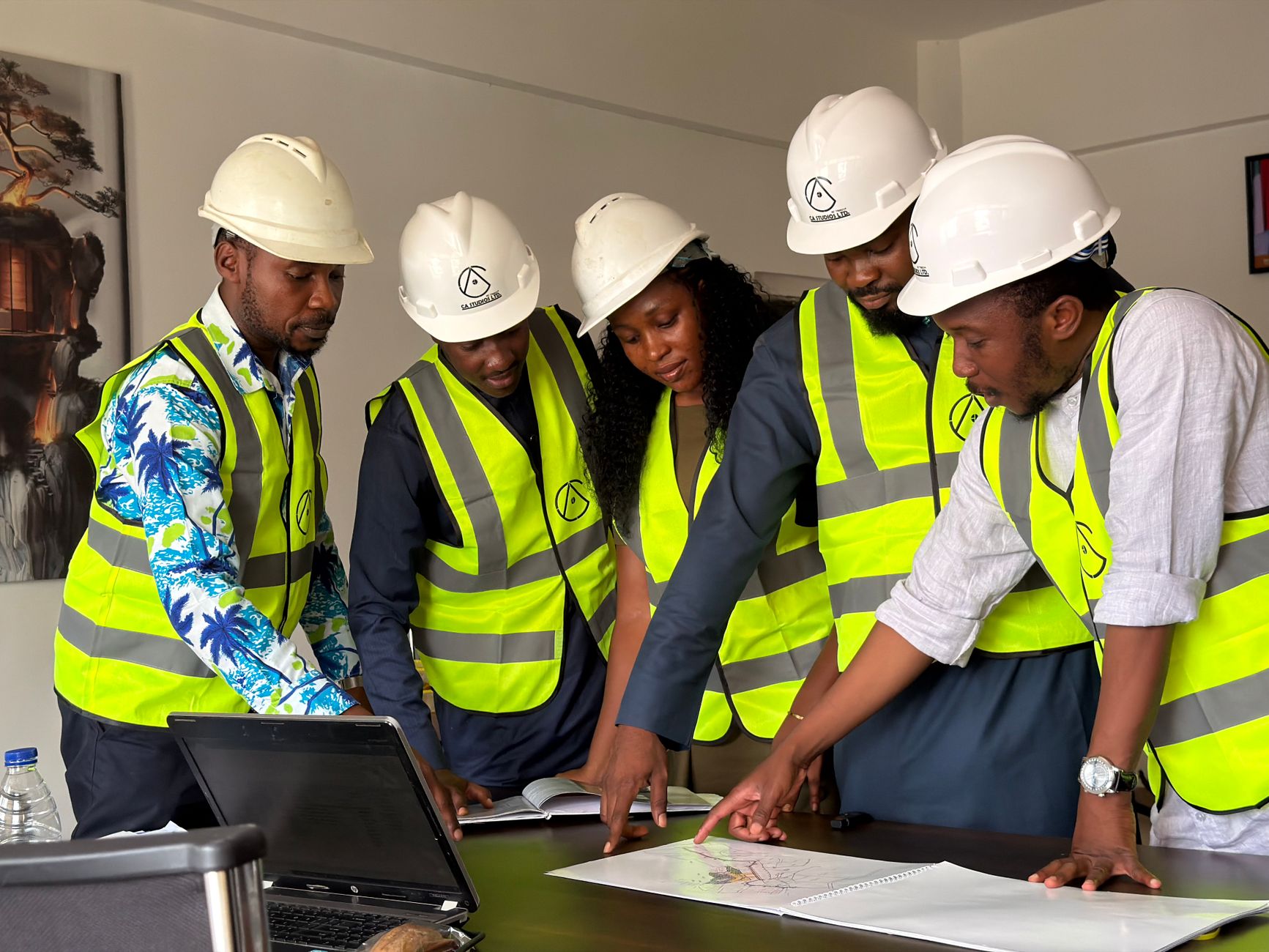 A project team in hi-vis reviewing construction drawings together around a laptop.